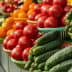 Baskets of cucumbers and tomatoes arranged in a market setting with vibrant colors. - Olive Oil Times