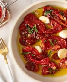 Bowl of marinated sun-dried tomatoes with garlic and herbs in olive oil. - Olive Oil Times