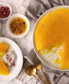 A round saffron rice dessert with a portion removed, served with yogurt and dried fruits. - Olive Oil Times