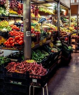A market aisle filled with various fruits and vegetables displayed on shelves and crates. - Olive Oil Times