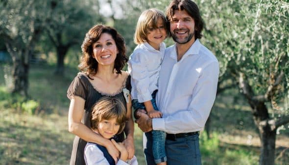 A family of four posing together in an olive grove, with two adults and two children. - Olive Oil Times