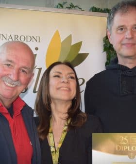 Three individuals posing together while holding a diploma at an event. - Olive Oil Times