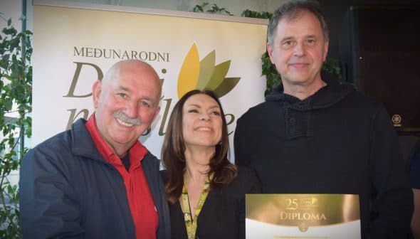 Three individuals posing together while holding a diploma at an event. - Olive Oil Times