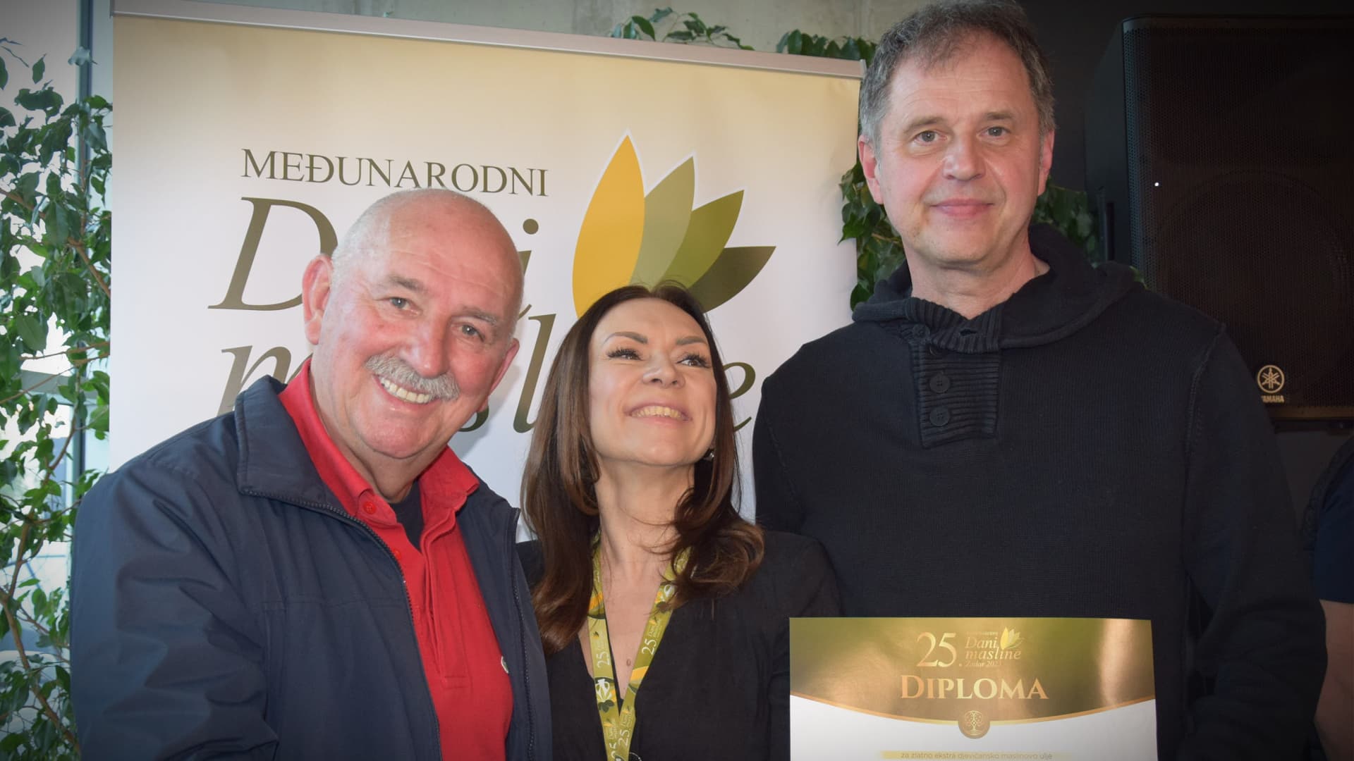 Three individuals posing together while holding a diploma at an event. - Olive Oil Times