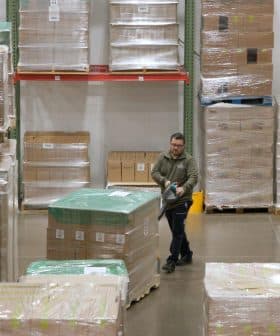 Warehouse worker using a pallet jack to move a large pallet in a storage facility. - Olive Oil Times