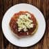 A plate of dakos salad featuring a base of barley rusk topped with tomato sauce and crumbled feta cheese. - Olive Oil Times
