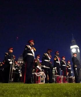 A group of ceremonial guards in uniform standing in formation at night with Big Ben in the background. - Olive Oil Times