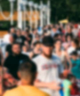 A large group of people walking together in a public area, blurred image showing diverse individuals. - Olive Oil Times