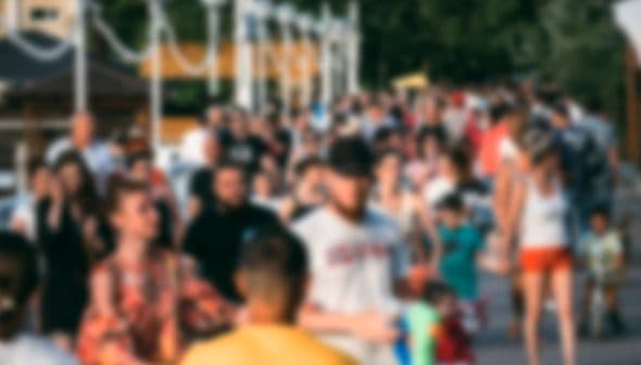 A large group of people walking together in a public area, blurred image showing diverse individuals. - Olive Oil Times