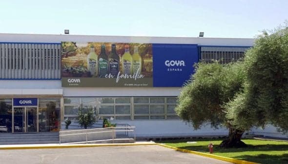 Exterior view of the Goya España building featuring a large advertisement and olive trees. - Olive Oil Times