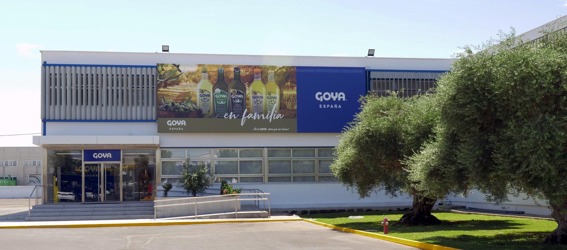 Exterior view of the Goya España building featuring a large advertisement and olive trees. - Olive Oil Times
