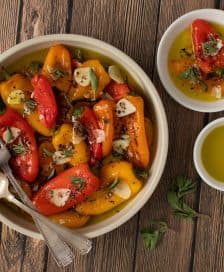Bowl of roasted bell peppers with garlic and herbs, served with olive oil on the side. - Olive Oil Times