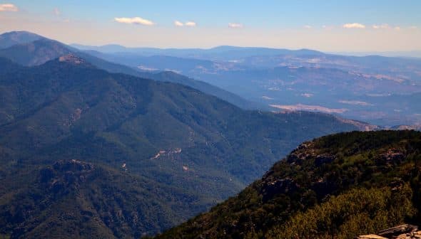 Expansive view of a mountain landscape featuring rolling hills and distant peaks under a clear blue sky. - Olive Oil Times