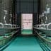 Interior view of a processing facility with stainless steel oil storage tanks and pipes. - Olive Oil Times