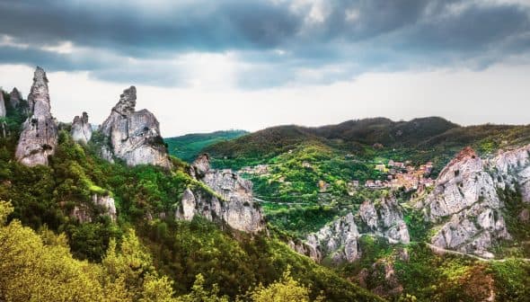 A panoramic view of a mountainous landscape featuring prominent rock formations and greenery. - Olive Oil Times