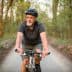 Older man wearing a helmet riding a bicycle on a forest trail during daylight. - Olive Oil Times
