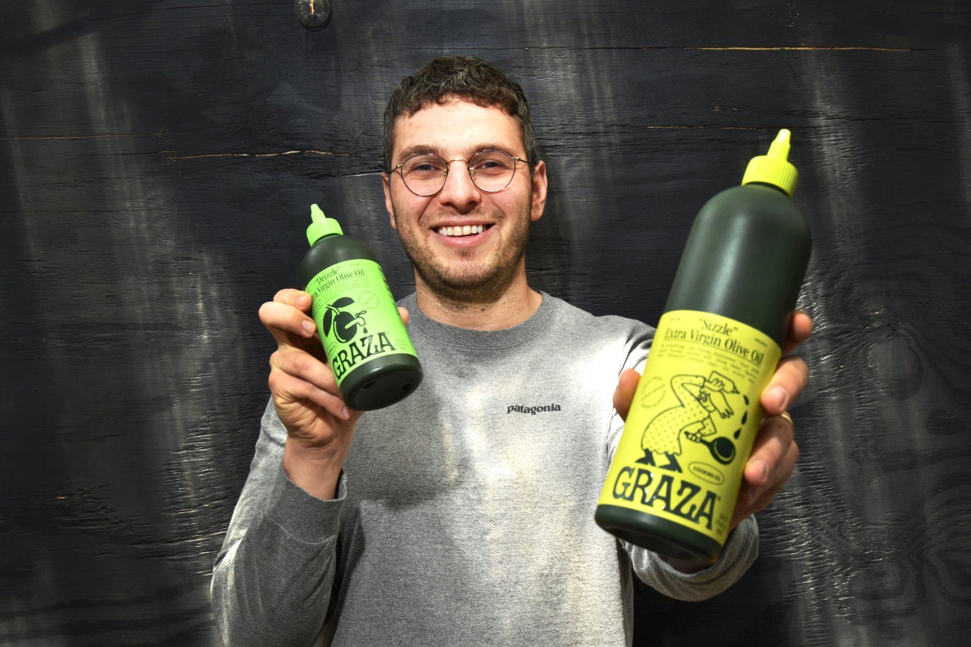 Person holding two bottles of Grazia extra virgin olive oil, one large and one small, both with green labels. - Olive Oil Times