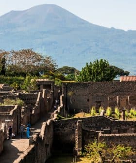 Ancient ruins of Pompeii with Mount Vesuvius visible in the background under clear skies. - Olive Oil Times