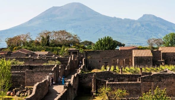 Ancient ruins of Pompeii with Mount Vesuvius visible in the background under clear skies. - Olive Oil Times