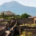 Ancient ruins of Pompeii with Mount Vesuvius visible in the background under clear skies. - Olive Oil Times