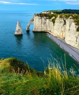Cliffs and a prominent rock formation in the sea at Etretat, France, under a clear blue sky. - Olive Oil Times