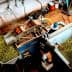 Worker processing olives in a facility with machinery and green olives in containers. - Olive Oil Times