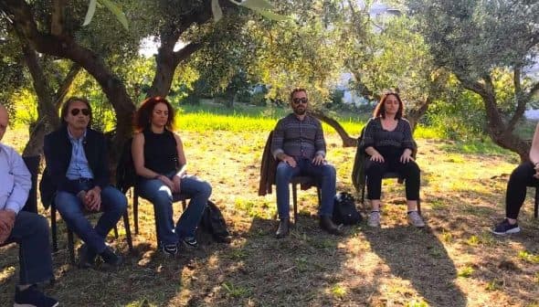 A group of individuals seated in an olive grove participating in a meditation session. - Olive Oil Times