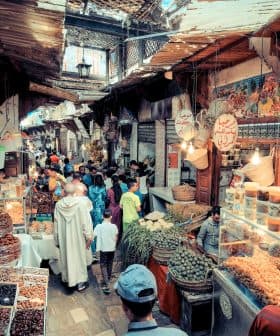 A bustling market scene in a traditional bazaar with various stalls and shoppers. - Olive Oil Times