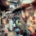 A bustling market scene in a traditional bazaar with various stalls and shoppers. - Olive Oil Times