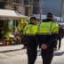 Two police officers in green and black uniforms walking in an urban area with a flower shop in the background. - Olive Oil Times