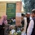 Exhibition booth featuring olive oil products and promotional materials at an event. - Olive Oil Times