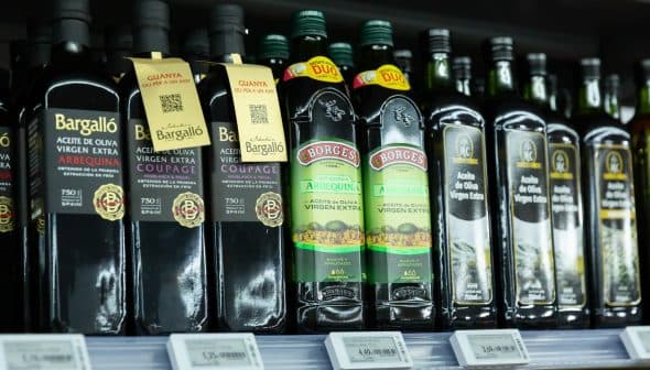 Various bottles of extra virgin olive oil displayed on a supermarket shelf. - Olive Oil Times