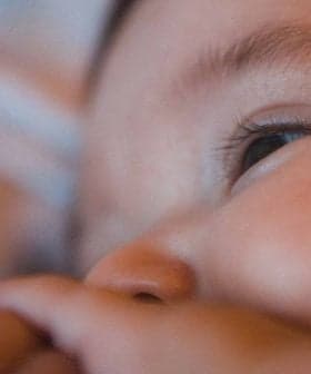 Close-up view of a baby's face with a focus on the eye and hand. - Olive Oil Times