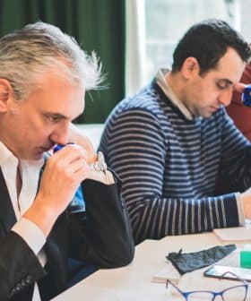 Three men participating in a tasting session, focusing on their individual tasks and using tasting tools. - Olive Oil Times