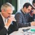 Three men participating in a tasting session, focusing on their individual tasks and using tasting tools. - Olive Oil Times