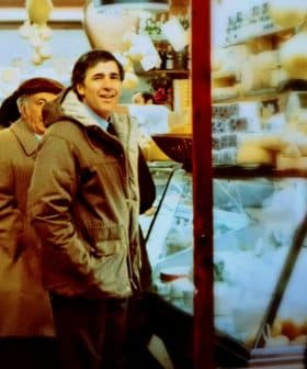 Two men standing in a market with shelves displaying various food items and products. - Olive Oil Times