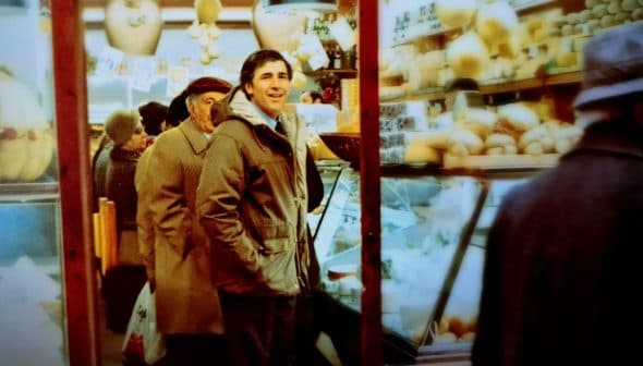 Two men standing in a market with shelves displaying various food items and products. - Olive Oil Times