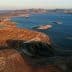 Aerial view of a reservoir with dry land and hills in the background during sunset. - Olive Oil Times
