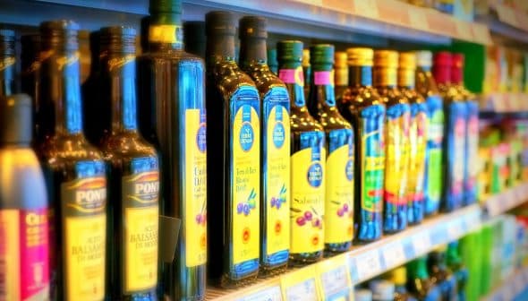 Various bottles of olive oil displayed on a shelf in a grocery store. - Olive Oil Times