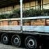 Truck transporting wooden crates filled with olive branches on a flatbed trailer. - Olive Oil Times