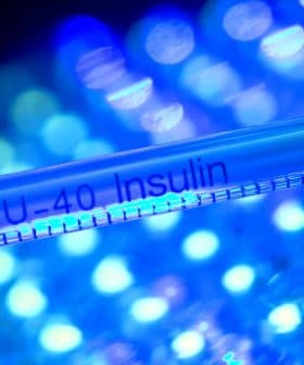 Close-up of a U-40 insulin syringe with a red cap against a blue and green background. - Olive Oil Times