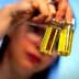 Person holding two small glass bottles containing olive oil with yellow liquid inside. - Olive Oil Times