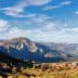 Scenic view of mountains with a small village nestled in the valley under a blue sky. - Olive Oil Times