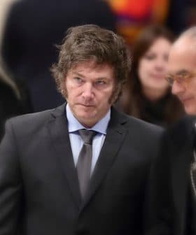 Two men in formal attire walking together at an event, one wearing a suit and tie, the other in a tuxedo. - Olive Oil Times