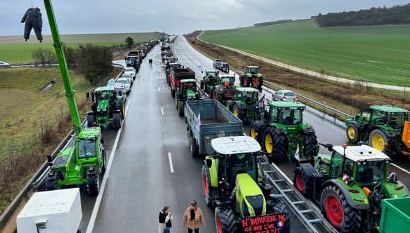 Line of tractors on a highway during a protest with people walking nearby. - Olive Oil Times