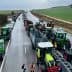 Line of tractors on a highway during a protest with people walking nearby. - Olive Oil Times