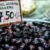 A bowl of black Kalamata olives displayed for sale with a price tag of 7.50 euros. - Olive Oil Times