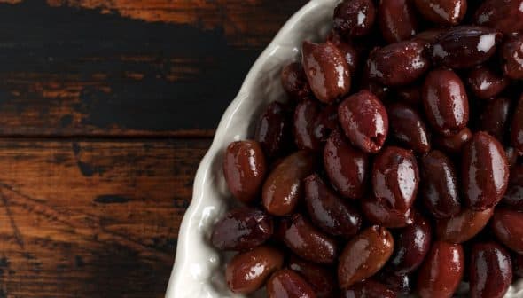 A close-up view of a bowl filled with various types of olives, showcasing their dark and light hues. - Olive Oil Times