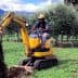Operator using a mini excavator to dig in an olive grove surrounded by olive trees. - Olive Oil Times