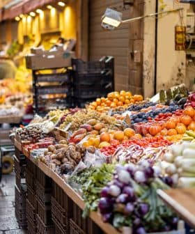 Vibrant display of various fruits and vegetables in a market setting with carts and crates. - Olive Oil Times